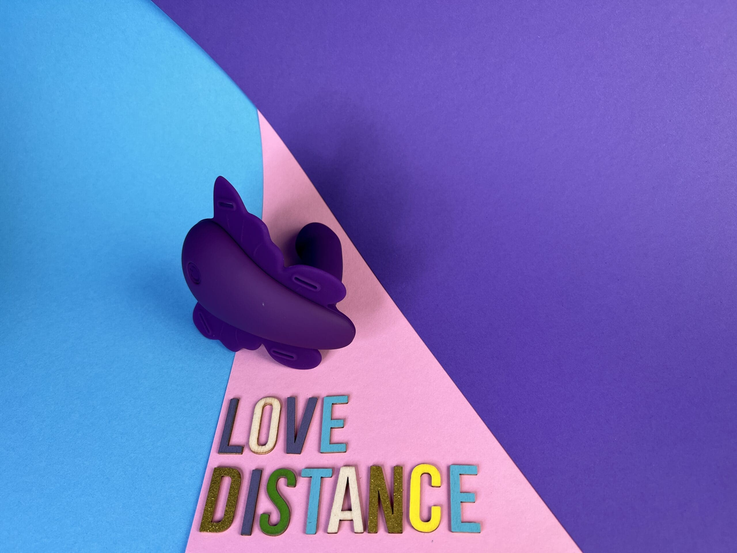 De Love Distance Reach G op een gekleurd ondergrondje met daaronder in losse lettertjes de merknaam.