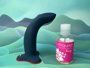 De fun factory limba flex large gebogen naast een flesje sliquid sassy.