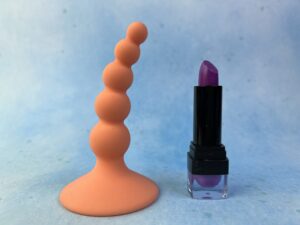 Linda. Kralen bootyplug naast een lipstick.