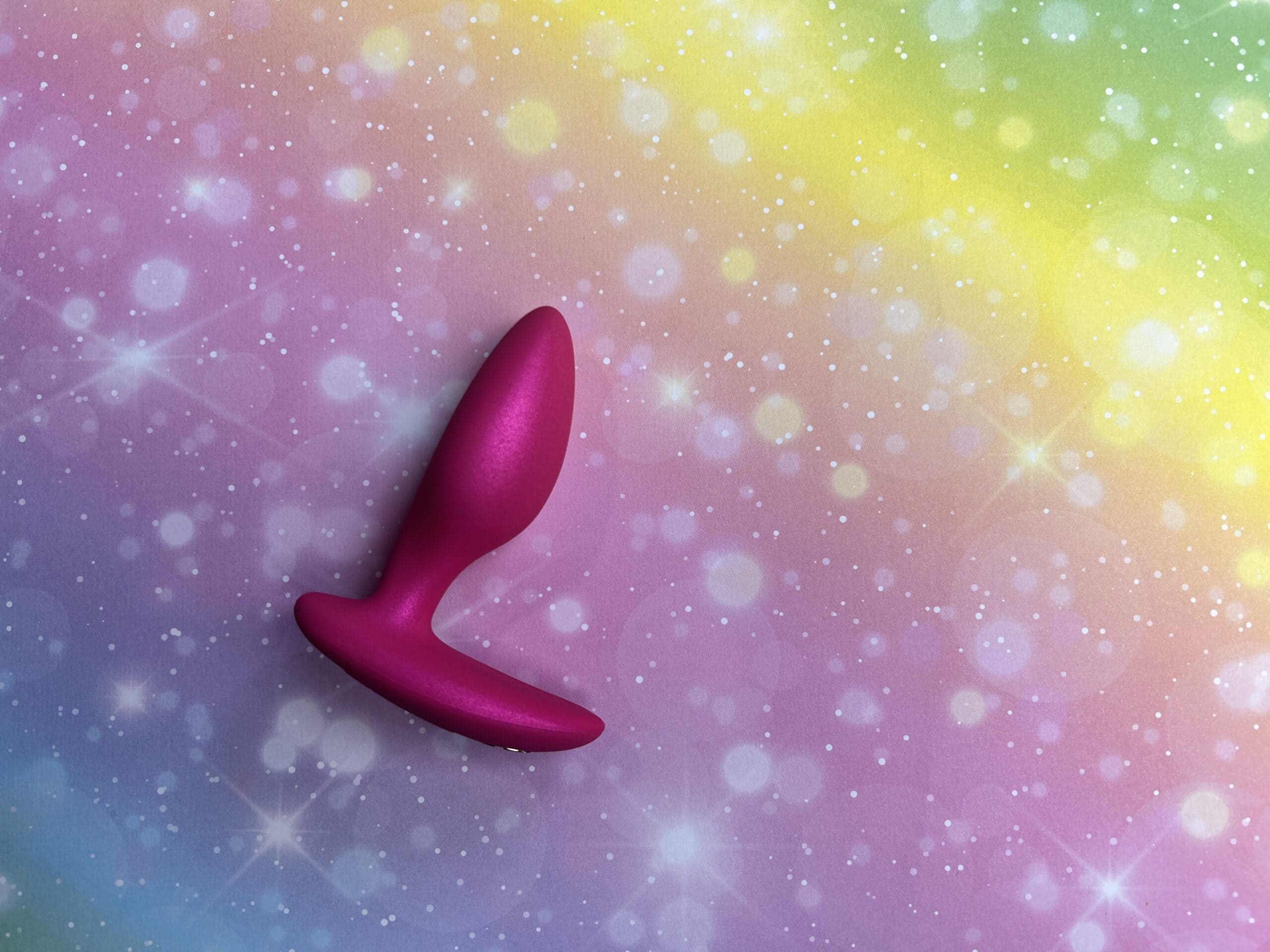 De We-Vibe Ditto + op een regenboogachtergrondje.