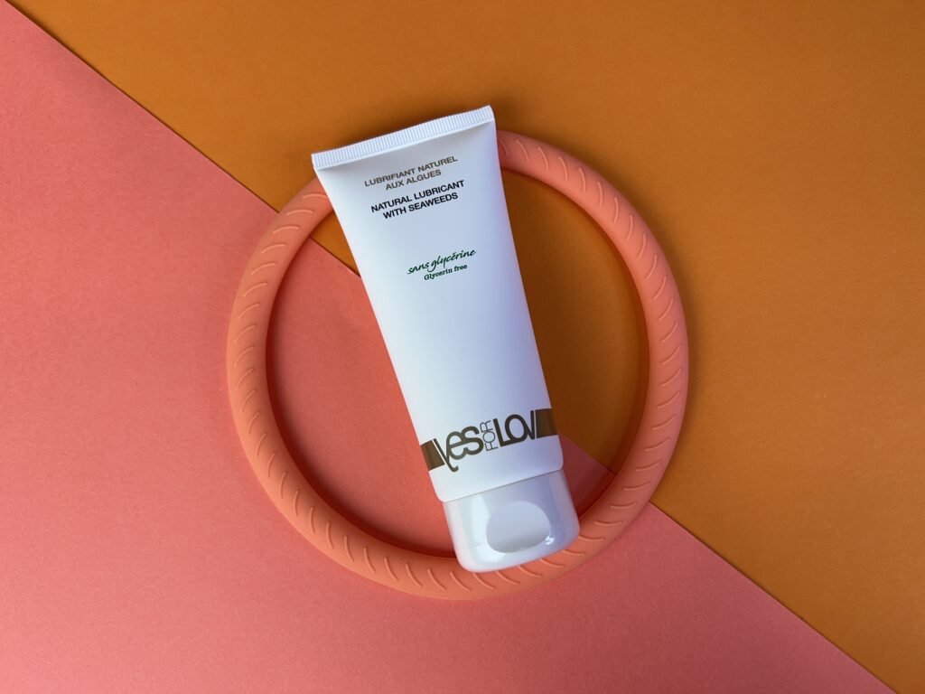 De tube yes for love natural lubricant in een cirkel, op een roze en oranje ondergrondje.