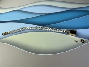 De sex & mischief pearl day collar  op een blauw en wit ondergrondje.