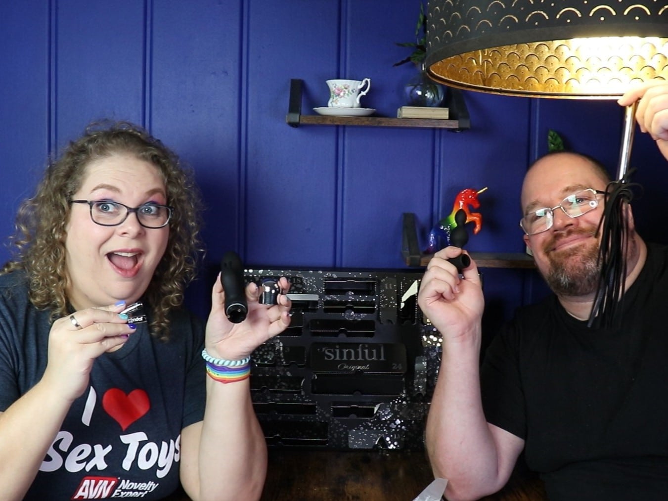 Tess en Jay zitten aan de keukentafel. Tess houdt een toy met batterijen vast en kijkt licht geshokeerd. Jay houdt een klein strokenzweepje vast.