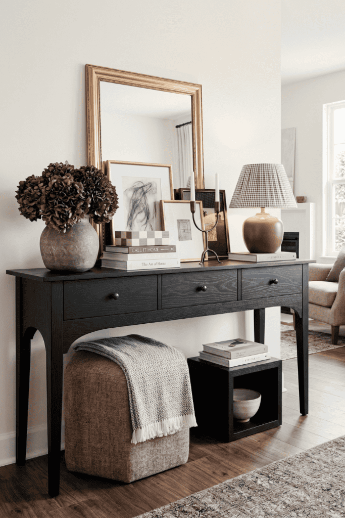 Elegant living room console table decor with mirror, artwork, and accessories.