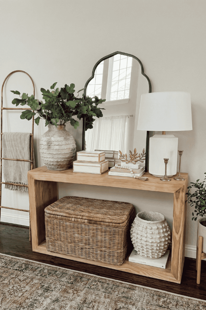 Living room console table decor with mirror, lamp, and greenery for stylish home accents.