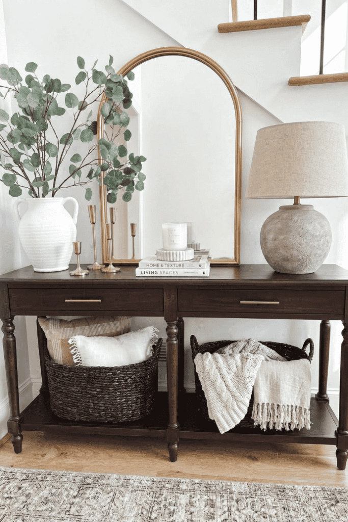 Living room console table decor with mirror, lamp, and greenery for stylish home accents.