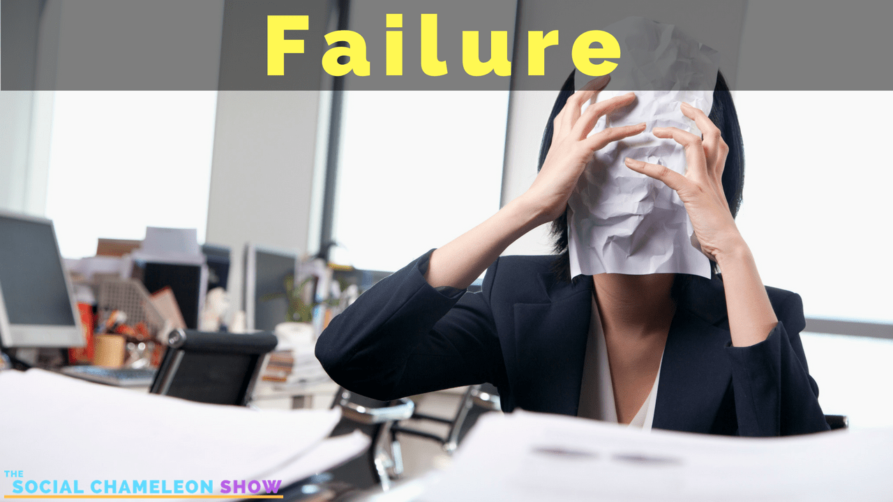 A frustrated woman in a business suit covers her face with a crumpled paper with the word "Failure" displayed in large letters overhead, amidst a cluttered office desk.