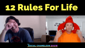 Two men in a video podcast; one smiling and wiping his eye, wearing a casual shirt, and the other wearing a bright orange squid hat, adjusting it with an amused expression. text reads "12 rules for life - the social chameleon show.