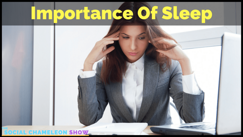A woman in a gray suit sits at a desk looking tired, with her hands near her temples. A laptop is open in front of her. The text "Importance Of Sleep" appears at the top of the image.
