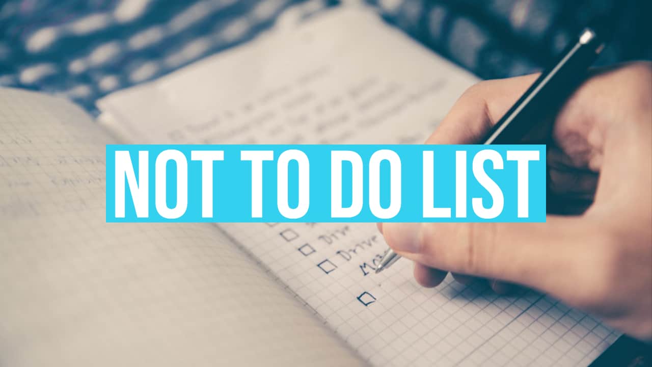 A person writes a "Making Your Not To Do List" in a notebook, with a pen in hand. The list includes checkboxes and is shown in close-up with a blurred background.