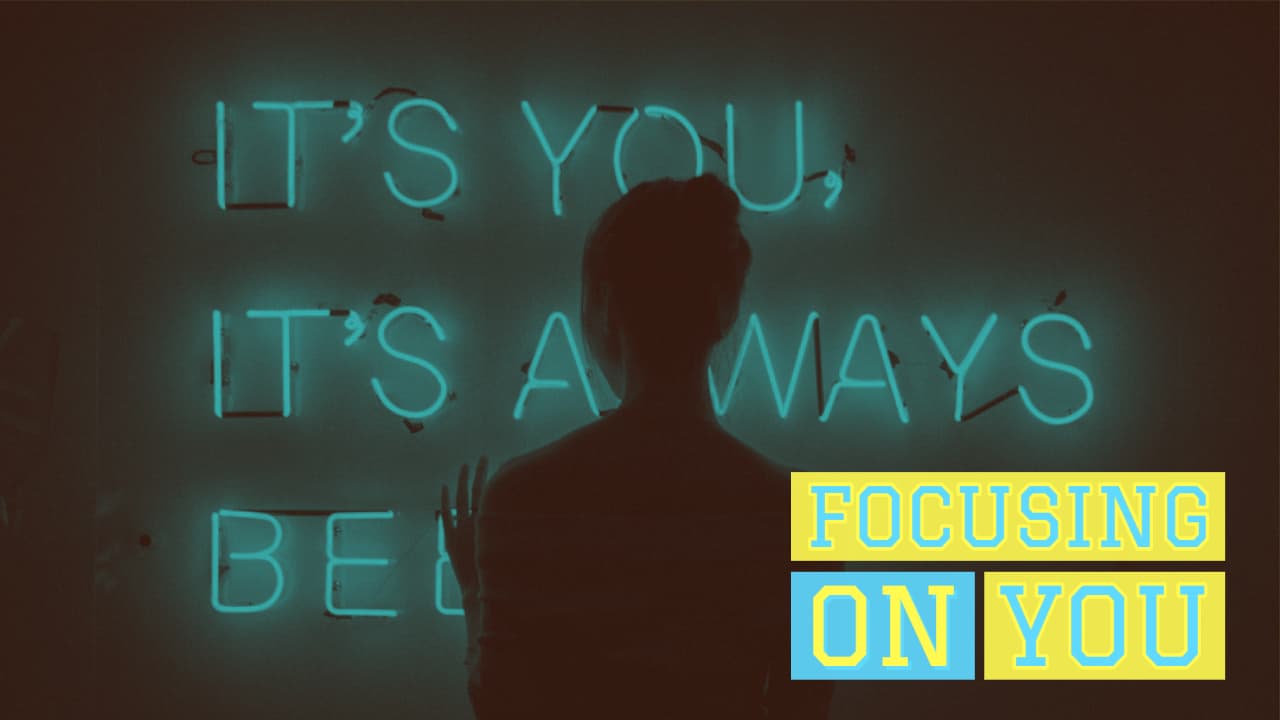Silhouetted person stands before a glowing neon sign that reads "it's you, it's always been you" with added text below saying "Focusing On You" in yellow.