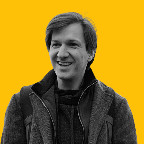 Smiling Mathias Fiedler with short hair, wearing a coat and sweater, carrying a backpack. Against a solid yellow background, they exude the confidence of a Social Chameleon Show guest, effortlessly blending into any universe they encounter.