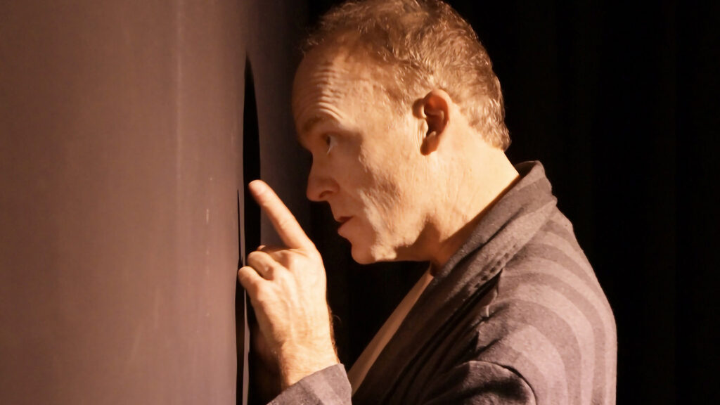 A performer from The StageCrafts passionately delivering a monologue on stage, emphasizing expressive gestures and intense focus.