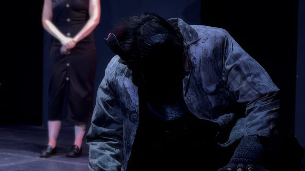 Performer in dark costume bowing on stage at MythicFest 2026, a sci-fi and fantasy arts festival in Hollywood, showcasing theatrical and cosplay performances.