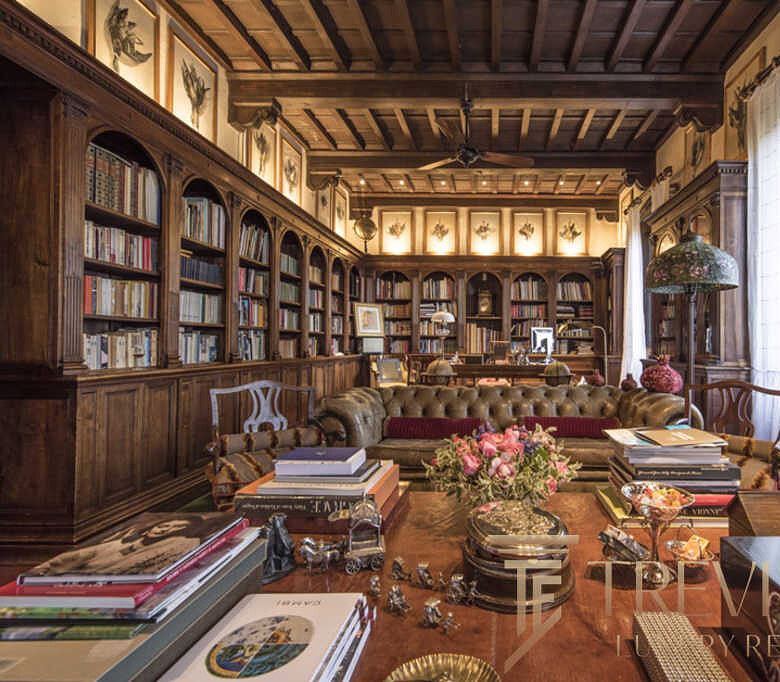 Роскошный домашний кабинет с деревянными книжными полками, антикварной мебелью и уютным мягким диваном, создающими атмосферу эксклюзивности и комфорта для высокого уровня жизни.