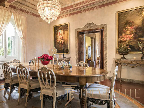 Роскошная столовая с антикварной мебелью и богатым декором, просторные окна с тяжелыми шторами, изысканное освещение, идеальное пространство для эксклюзивных мероприятий и семейных ужинов.