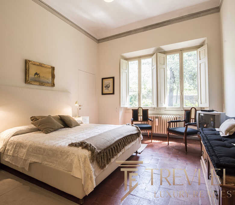 Уютная спальня с мягким светом и классической мебелью, большие окна пропускают много естественного света, создавая теплую атмосферу, идеально подходящую для роскошной недвижимости.