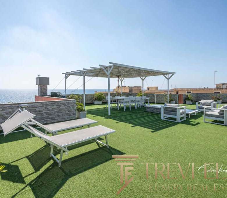 Роскошная терраса с видом на море, уютной зоной отдыха, шезлонгами и обеденной зоной под навесом, идеально подходит для роскошных вечеринок и релаксации на открытом воздухе.