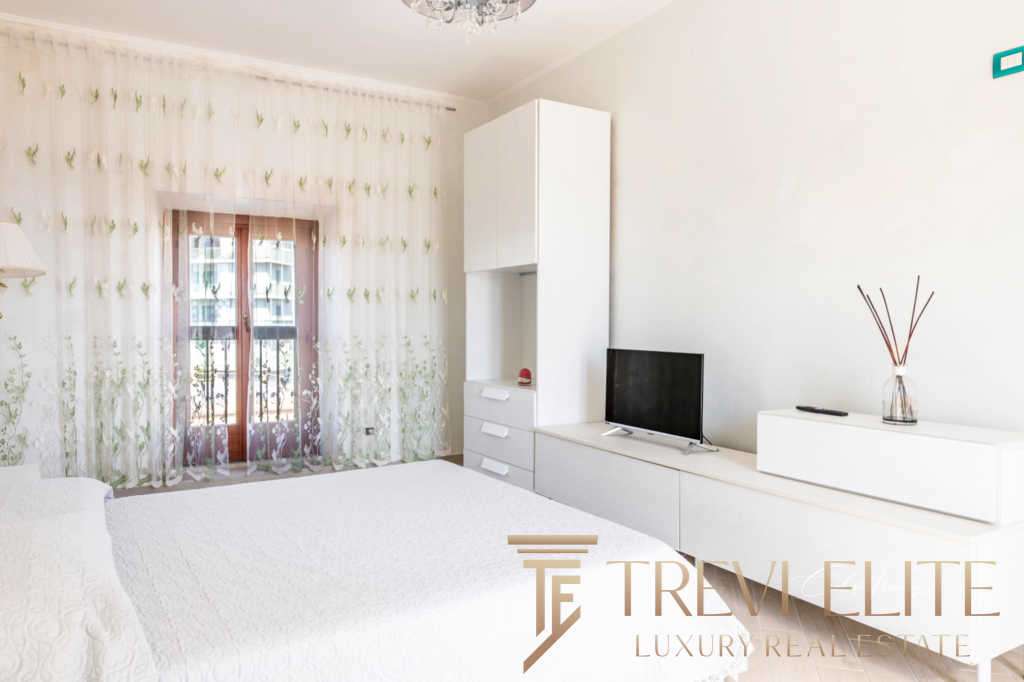 Элитная спальня с мягким светом, белой мебелью и современными деталями, привлекающая внимание к высокому уровню роскоши и комфорта в недвижимости Треви Элит.