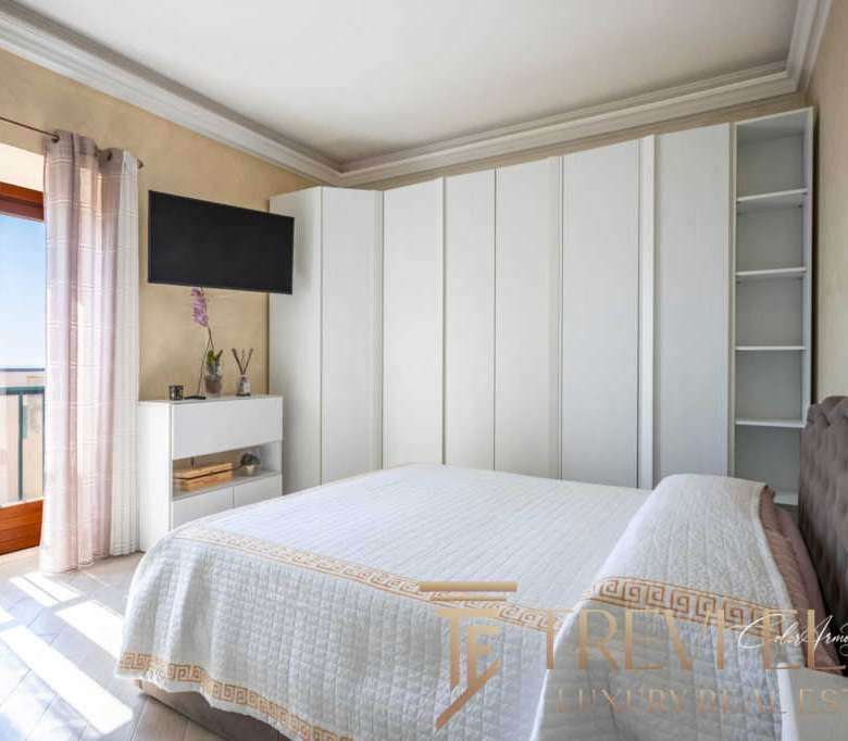 Уютная спальня в роскошной квартире с выходом на балкон, светлыми шторами и современным интерьером. Идеальное место для отдыха в элитной недвижимости от Треви Элит.