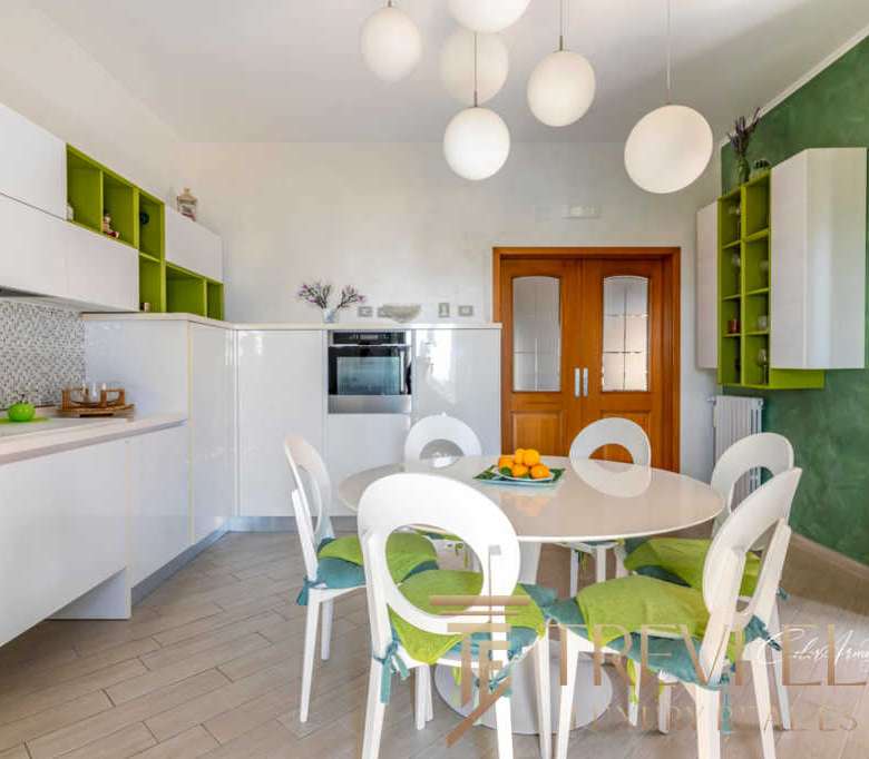 Элегантная кухня с белыми и зелеными акцентами, современная мебель и светлый интерьер, создающий уют и гармонию в роскошной недвижимости от Треви Элит.