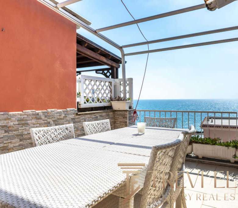Уютная терраса с видом на море, оборудованная для отдыха на открытом воздухе. Идеальное место для наслаждения солнечными днями и морским пейзажем в центре итальянского жилого комплекса.