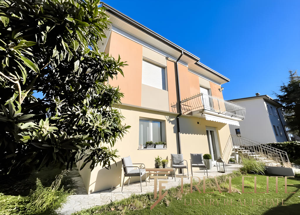 светлый жилой дом с просторной террасой и уютной зеленой зоной на заднем дворе, современные фасады, ухоженный ландшафт, представительство агентства недвижимости Треви Элит.