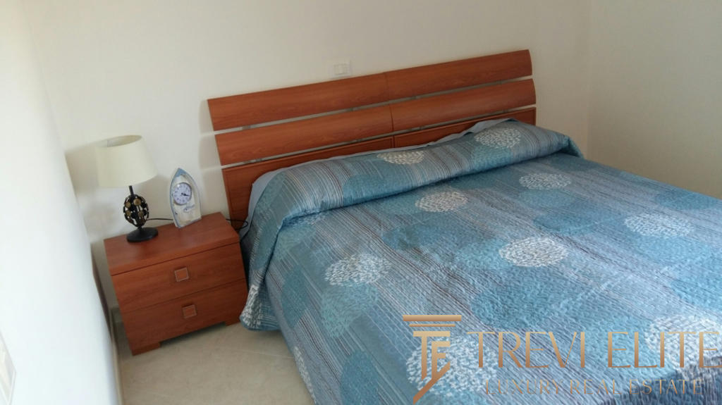 Современная спальня с деревянной кроватью и голубым постельным бельем в уютной комнате для комфортного отдыха.