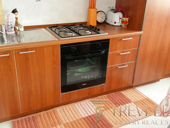 Современная кухня с деревянными фасадами, встроенной плитой и духовкой, раковиной и эстетичным интерьером для комфортной жизни.