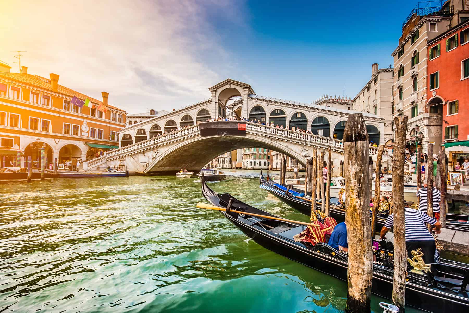 Punta Cana Gondolas floating on the canal in Venice with historic buildings and a bridge in the background.