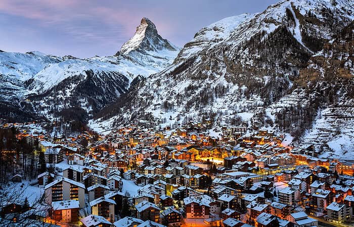 Punta Cana Snowy mountain village with illuminated buildings and the iconic Matterhorn peak in the distance.