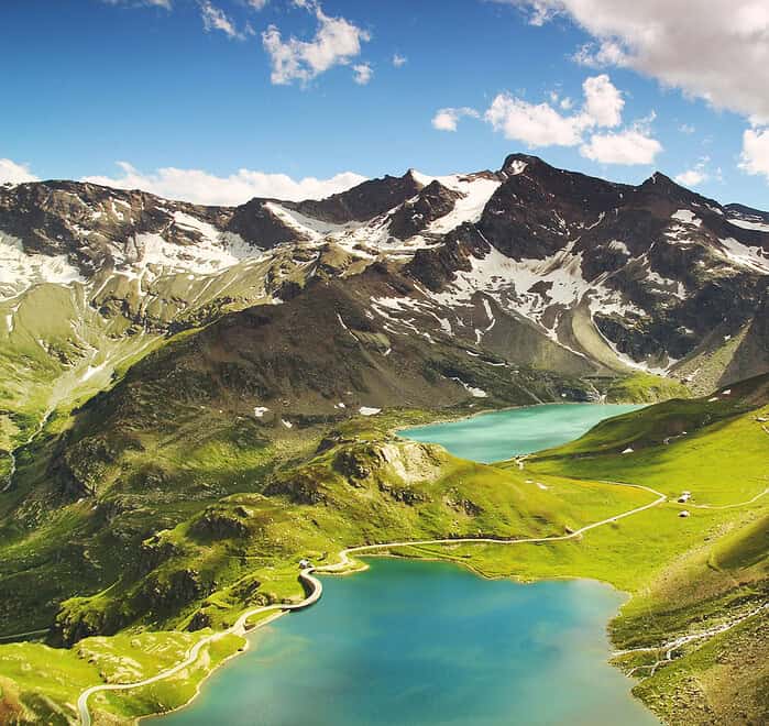 Punta Cana Scenic view of a turquoise mountain lake surrounded by lush green hills and towering peaks under a p.