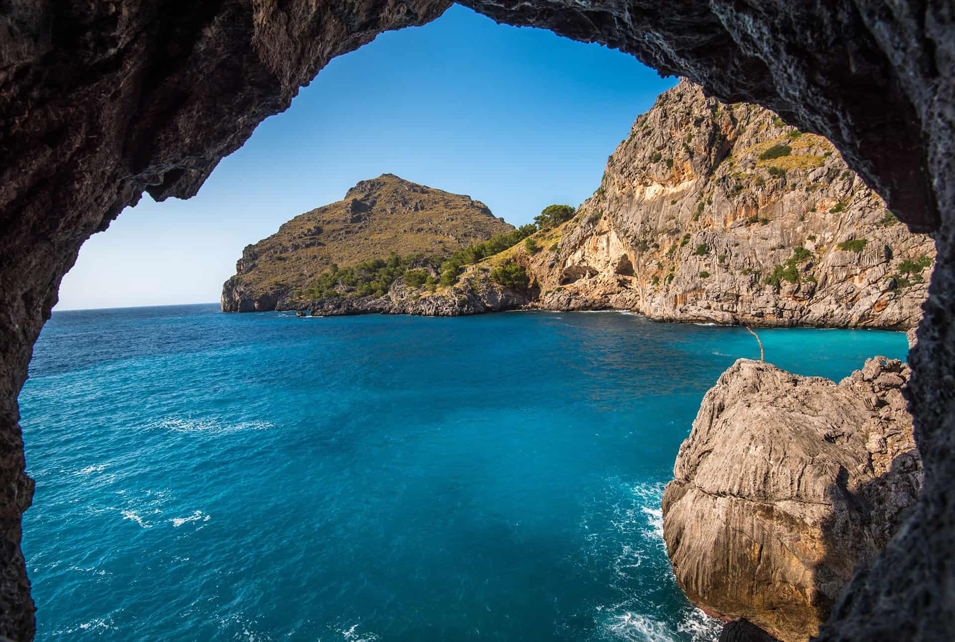 Punta Cana Scenic view of Punta Cana coast seen through a cave opening with cliffs and turquoise water.