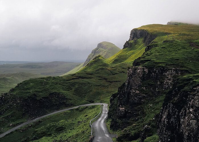 Punta Cana Scenic landscape of lush green cliffs and a curving road under cloudy skies.