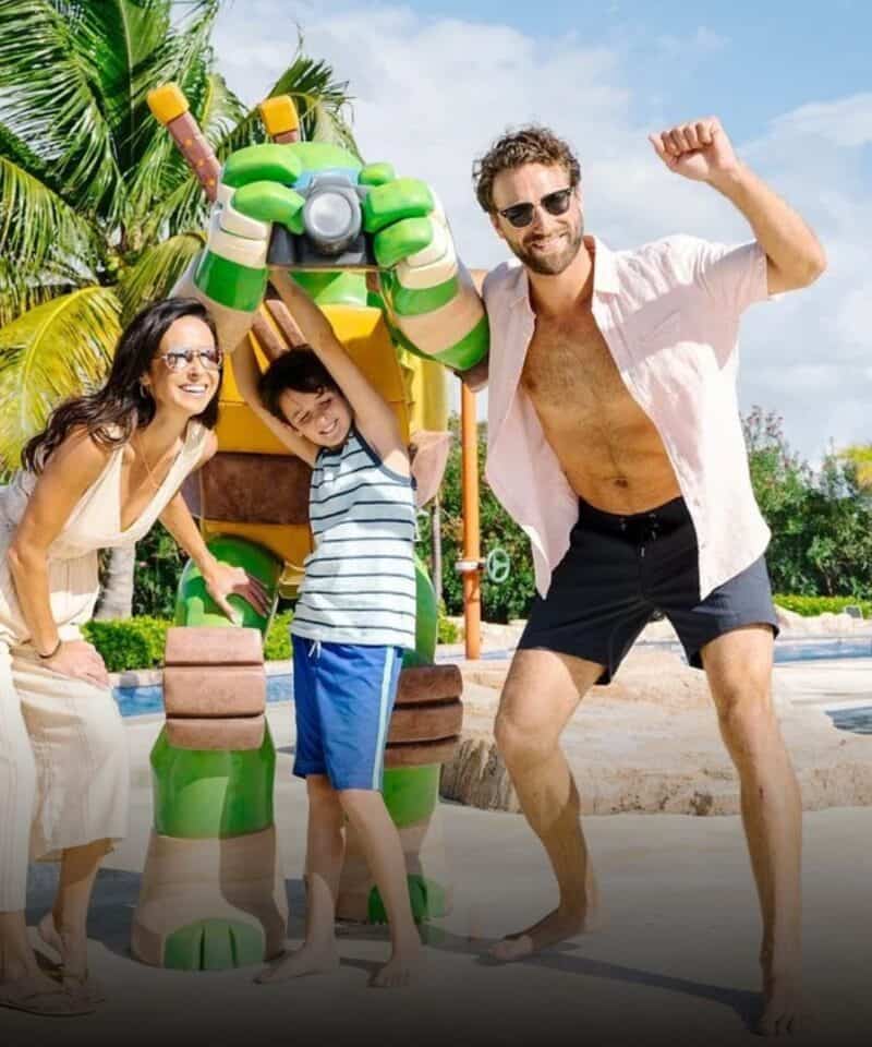 Punta Cana Family enjoying a playful moment with a Teenage Mutant Ninja Turtles statue at a resort in Bavaro, P.