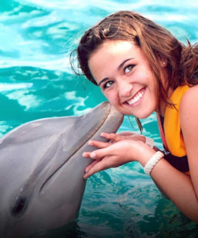 Punta Cana Smiling woman interacting with a dolphin in clear blue water in Punta Cana, Dominican Republic.