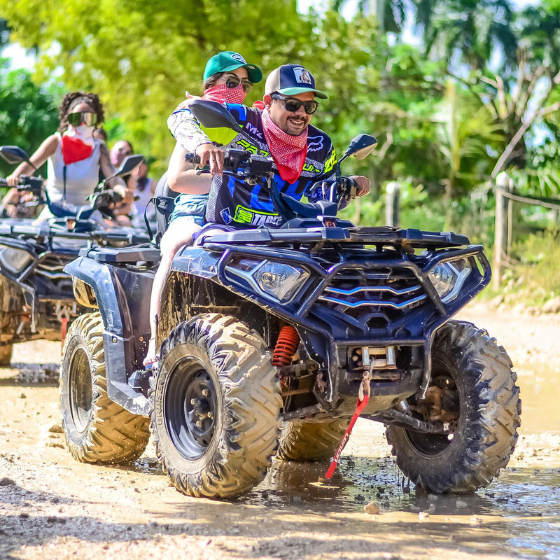 Punta Cana Group of people riding ATV quads through muddy terrain in Punta Cana, Dominican Republic.