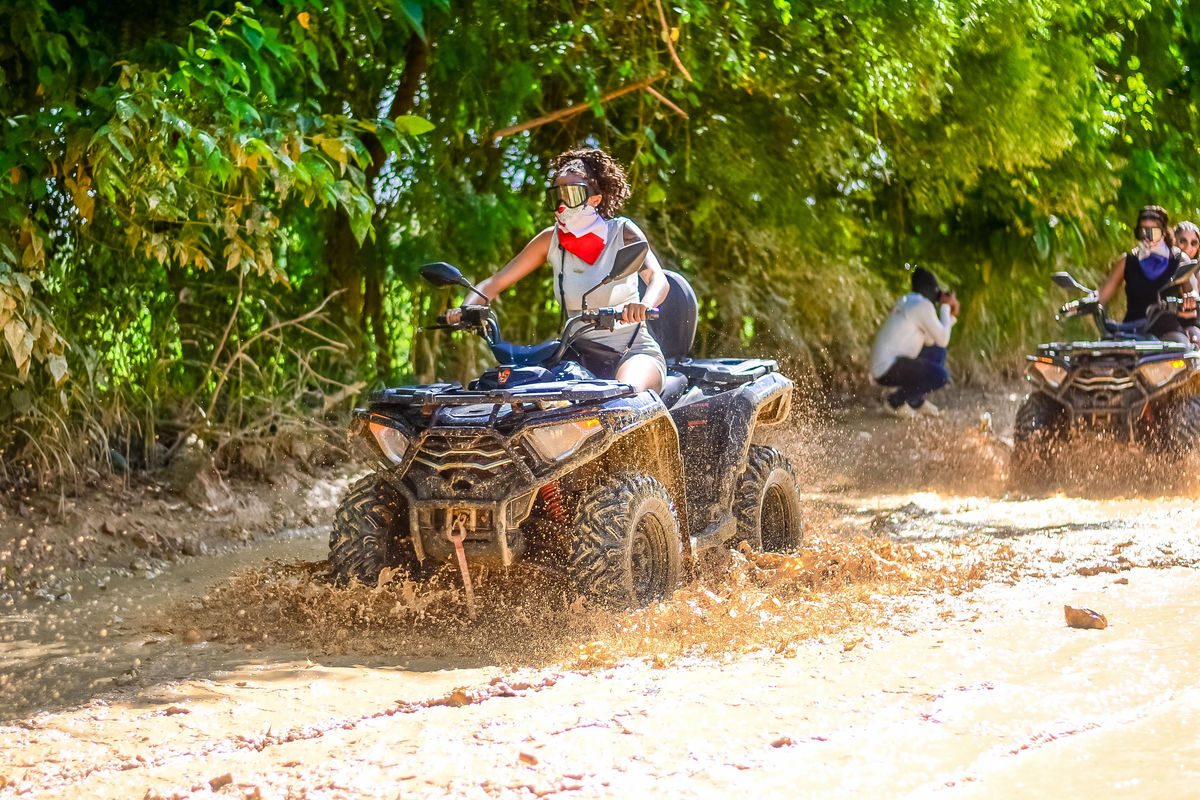 Punta Cana ATV riding through muddy trails in Punta Cana with lush green surroundings.