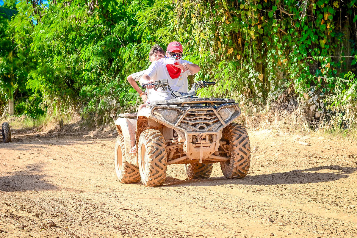 Punta Cana Two people riding a dirt ATV through a lush, green trail in Punta Cana, Dominican Republic.