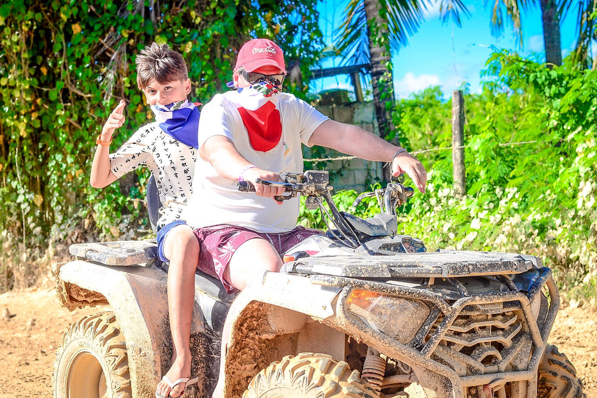 Punta Cana Two kids riding a dirt bike ATV in a tropical setting in Punta Cana, Dominican Republic.