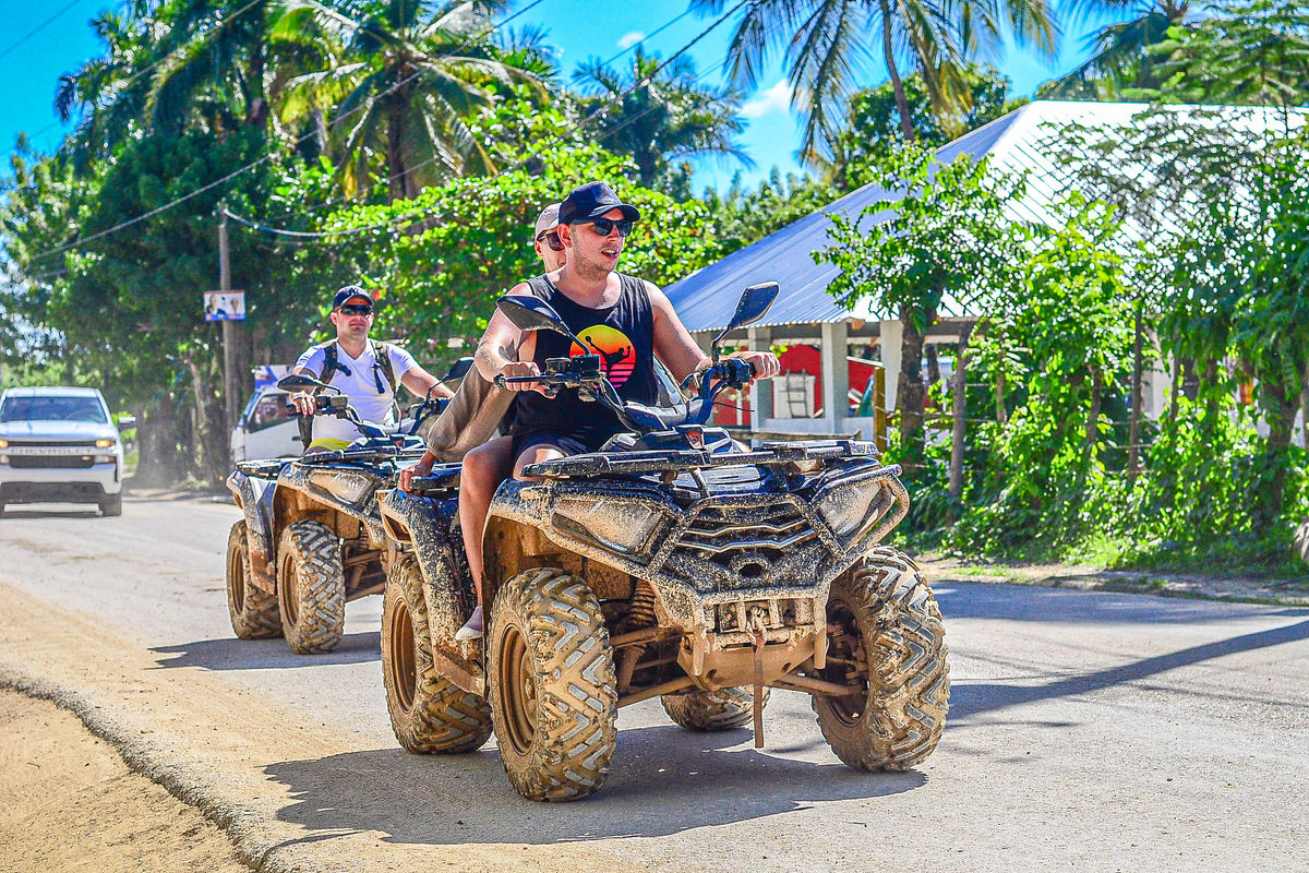 Punta Cana People riding ATVs on a sunny day with lush greenery and tropical trees in the background.
