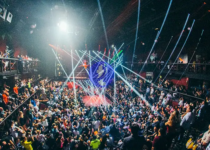 Punta Cana Nightclub scene with colorful lights, a lively crowd, and a stage with DJ or performers.