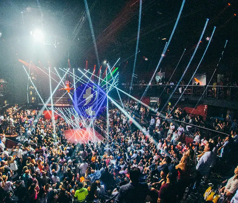 Punta Cana Nightclub scene with colorful lights, a lively crowd, and a stage with DJ or performers.