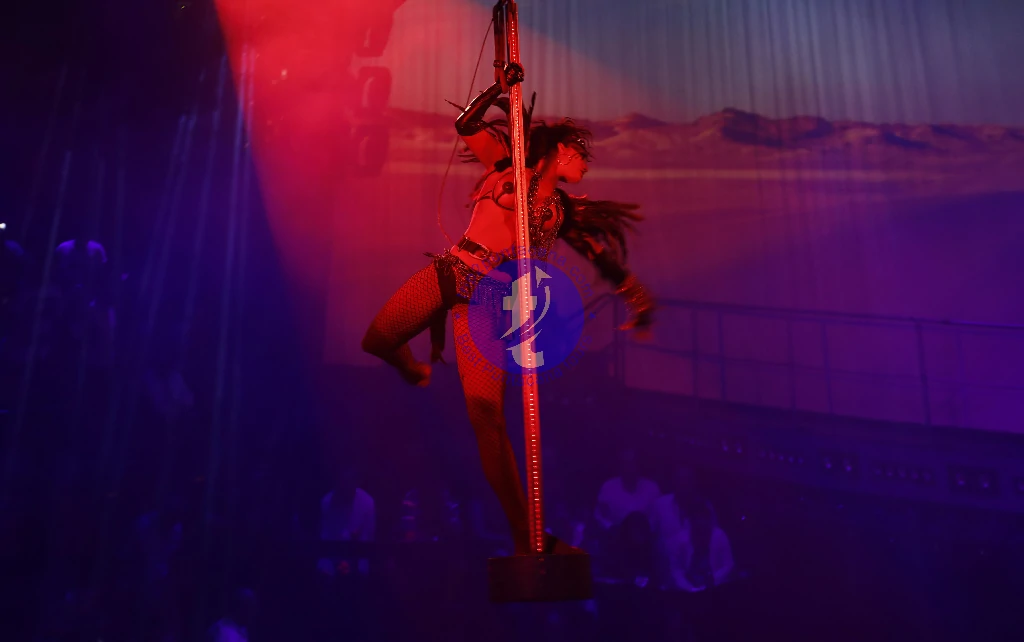 Punta Cana Pole dance performance at a nightclub with vibrant red and blue lighting.