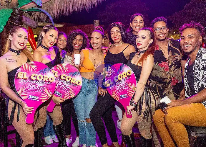 Punta Cana A lively group of friends enjoying a fun night out in Punta Cana, holding colorful signs and smiling.