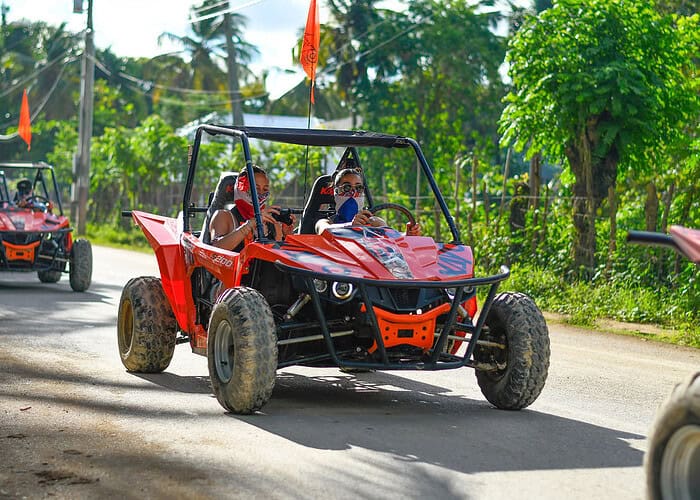 Punta Cana Exciting off-road buggy ride through lush Punta Cana landscape with tourists enjoying the adventure.