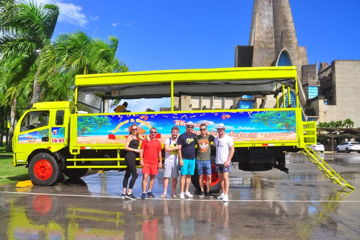 Punta Cana Vibrant open-air tour bus in Punta Cana with tourists, palm trees, and historic monument.
