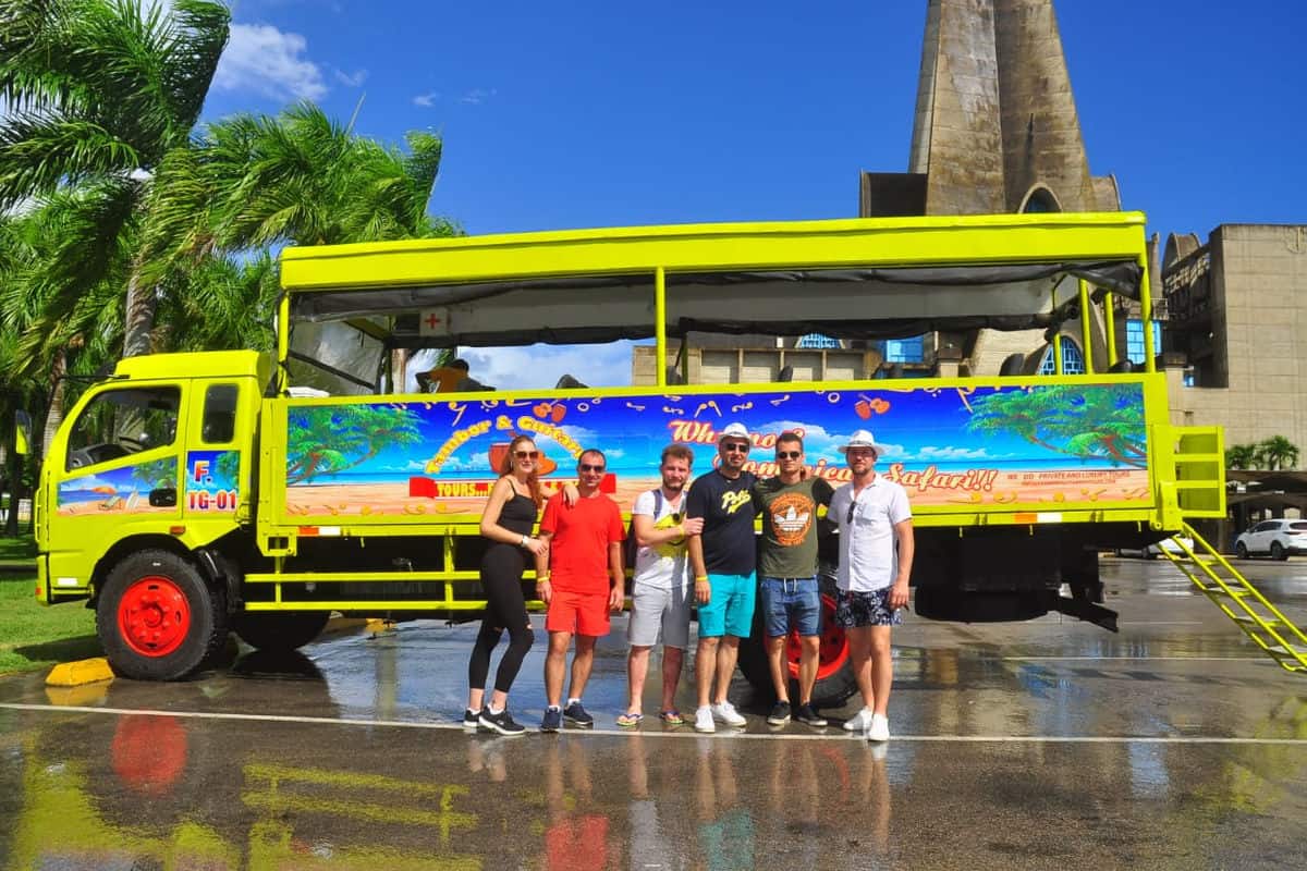 Punta Cana Tourists standing in front of a vibrant open-air bus in Punta Cana.