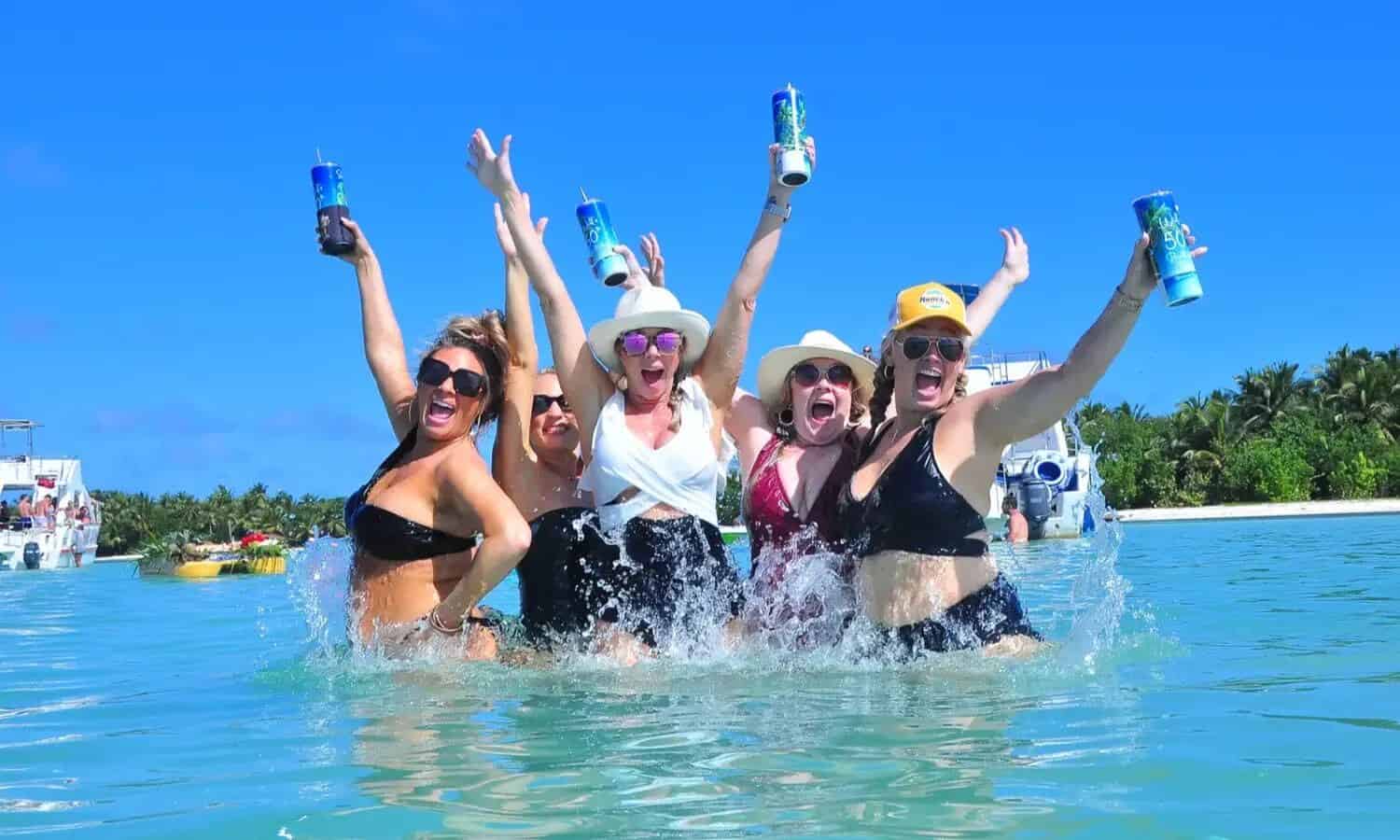Punta Cana Group of women celebrating with drinks in the water, smiling and having fun.