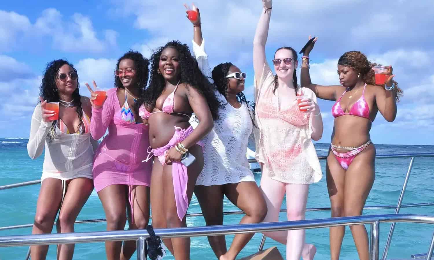 Punta Cana Group of women having fun on a catamaran, holding drinks, with the ocean and blue sky in the backgro.